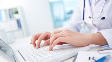 Close-up of hands of a nurse typing on laptop